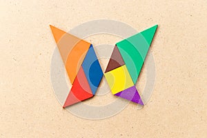 Color tangram in butterfly shape on wood background