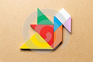 Color tangram in duck or swan shape on wood background