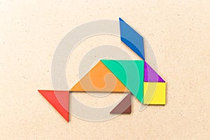 Color tangram in fish shape on wood background