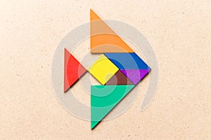 Color tangram in fish shape on wood background