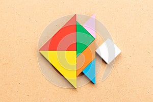 Color tangram in fish shape on wood background