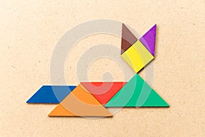 Color tangram in lying down cat shape on wood background