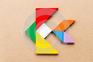Color tangram in fish shape on wood background