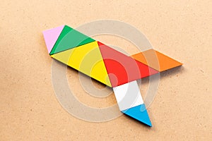 Color tangram in rocket or missile shape on wood bacground Concept for new experience, start up the business
