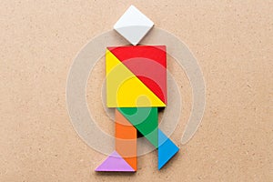 Color tangram in running or joy people shape on wood background