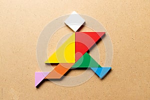 Color tangram in running man shape on wood background