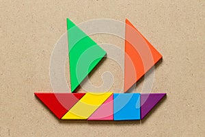 Color tangram in sail boat shape on wood background Concept for start the business or new journey