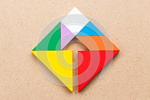 Color tangram in square with inside arrow sign shape on wood background Concept of Business direction, company vision or