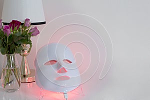 Color therapy mask, vase with roses and a lamp