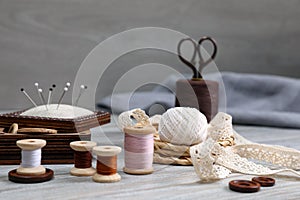 Color threads and different sewing accessories on white wooden table