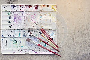 Color tray for water colors and various brushes on the cement fl