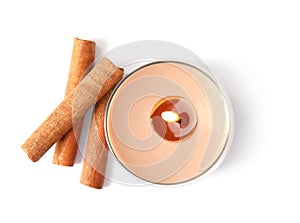 Color wax candle in glass holder and cinnamon sticks isolated on white, top