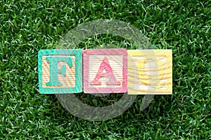 Color wood block in word FAQ Abbreviation of Frequently Asked Questions on green grass background