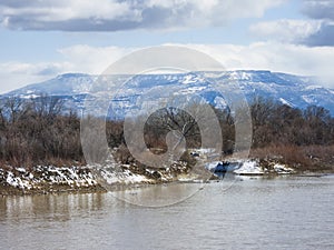 The Colorado River flows past banks dusted with fresh snow