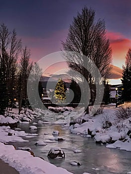 Colorado Ski Town Breckenridge. Frozen River and dramatic orange sunset with a Christmas tree