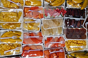 Colored background with fruits wrapped in cellophane with white plastic fork