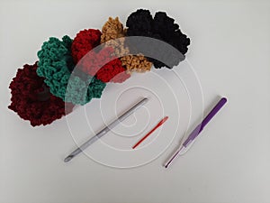 Colored balls of crochet thread, scissors and a needle on a white background