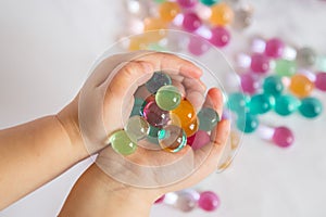 Colored balls of hydrogel in child`s palms. Sensory experiences