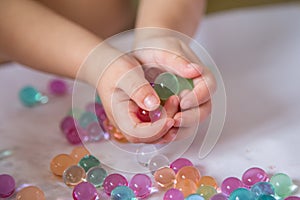 Colored balls of hydrogel in child`s palms. Sensory experiences