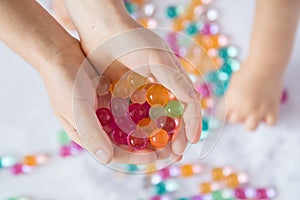 Colored balls of hydrogel in child`s palms. Sensory experiences