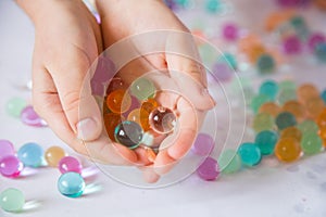 Colored balls of hydrogel in child`s palms. Sensory experiences