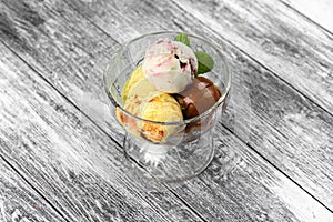 Colored balls of ice cream in a glass cremant on wooden grey background