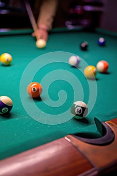 colored billiard balls with numbers on the billiard table in front of the pocket