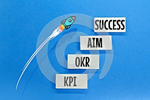 colored board with the letters KPI, OKR, AIM and success. concept towards success