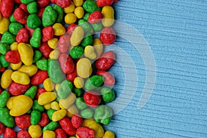 Colored bright texture of small chocolates on a blue table