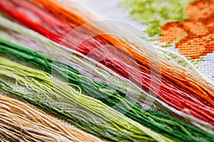 Colored bright threads for embroidery on a embroidered canvas.