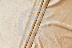 Colored brown textile satin fabric folded in folds and waves with highlights and texture