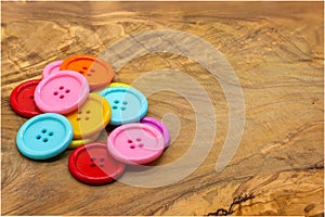 Colored buttons for clothes on a wooden table. Material for sewing.