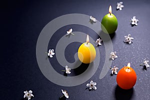 Colored candles in the shape of Easter egg with flowers on black