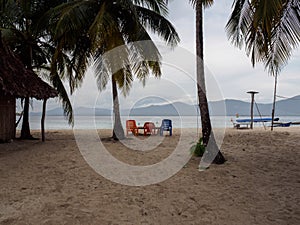 Colored chairs on the beach at Ina Island San Blas Panama, mountain range on the horizon