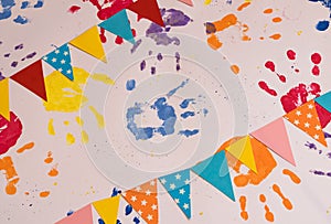 Colored children's hand prints and a garland of flags on a white background. Top view, flat position.