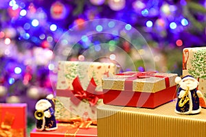 Colored Christmas presents under a Christmas tree with decorations and colorful lights.