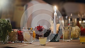 Colored cocktail ingridients in glasses and a candle stand on a bar counter