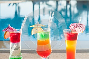 Colored cocktails on a background of water. Colorful cocktails near the pool. Beach party. Summer drinks.