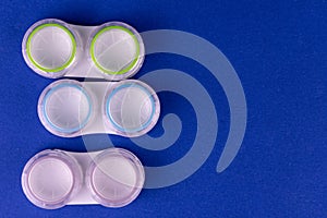 Colored containers for contact lenses for eyes on a blue background. Copy space.