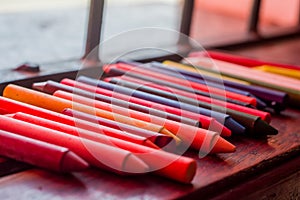 colored crayons, various colors of crayons on a wooden table with natural light and background window, diversity