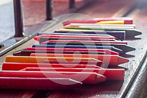 colored crayons, various colors of crayons on a wooden table with natural light and background window, diversity