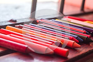 colored crayons, various colors of crayons on a wooden table with natural light and background window, diversity