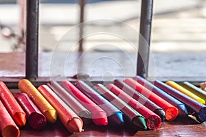 colored crayons, various colors of crayons on a wooden table with natural light and background window, diversity