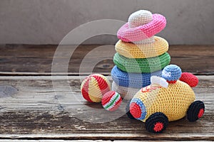 Colored crochet racing car and pyramid from colored rings. Toy for babies and toddlers to learn mechanical skills and colors.