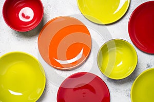 Colored dinnerware - red and green plates on light stone table.