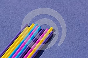 Colored disposable plastic straws on purple background