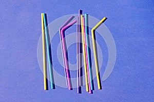 Colored disposable plastic straws on purple background