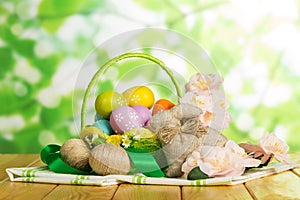 Colored Easter eggs in basket, intertwined cords, bunny, flowers