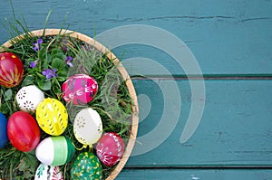 Colored Easter eggs in basket top view on wooden background. Happy Easter concept card. Happy Easter eggs on wooden background.