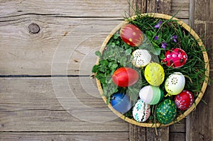 Colored Easter eggs in basket top view on wooden background. Happy Easter concept card. Happy Easter eggs on wooden background.